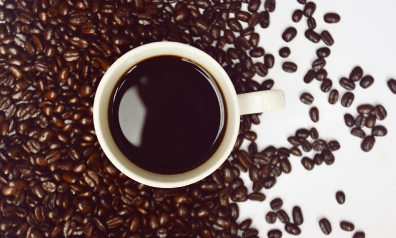 دانه های قهوه به همراه یک فنجان مملو از قهوه در یک قاب