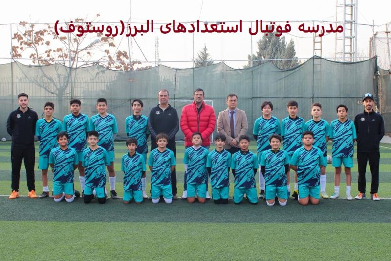 عکس تیم نوجوانان بهترین مدرسه فوتبال،ایران روستوف با لباسهای آبی در زمین چمن به همراه مربیان و نیما نکیسا